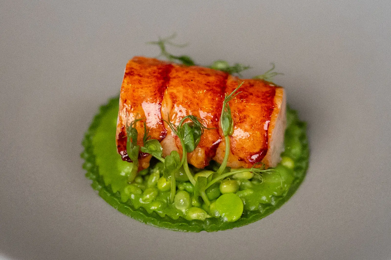 Blue lobster on a bright green sauce, from the summer 2026 menu at Blue by Alain Ducasse