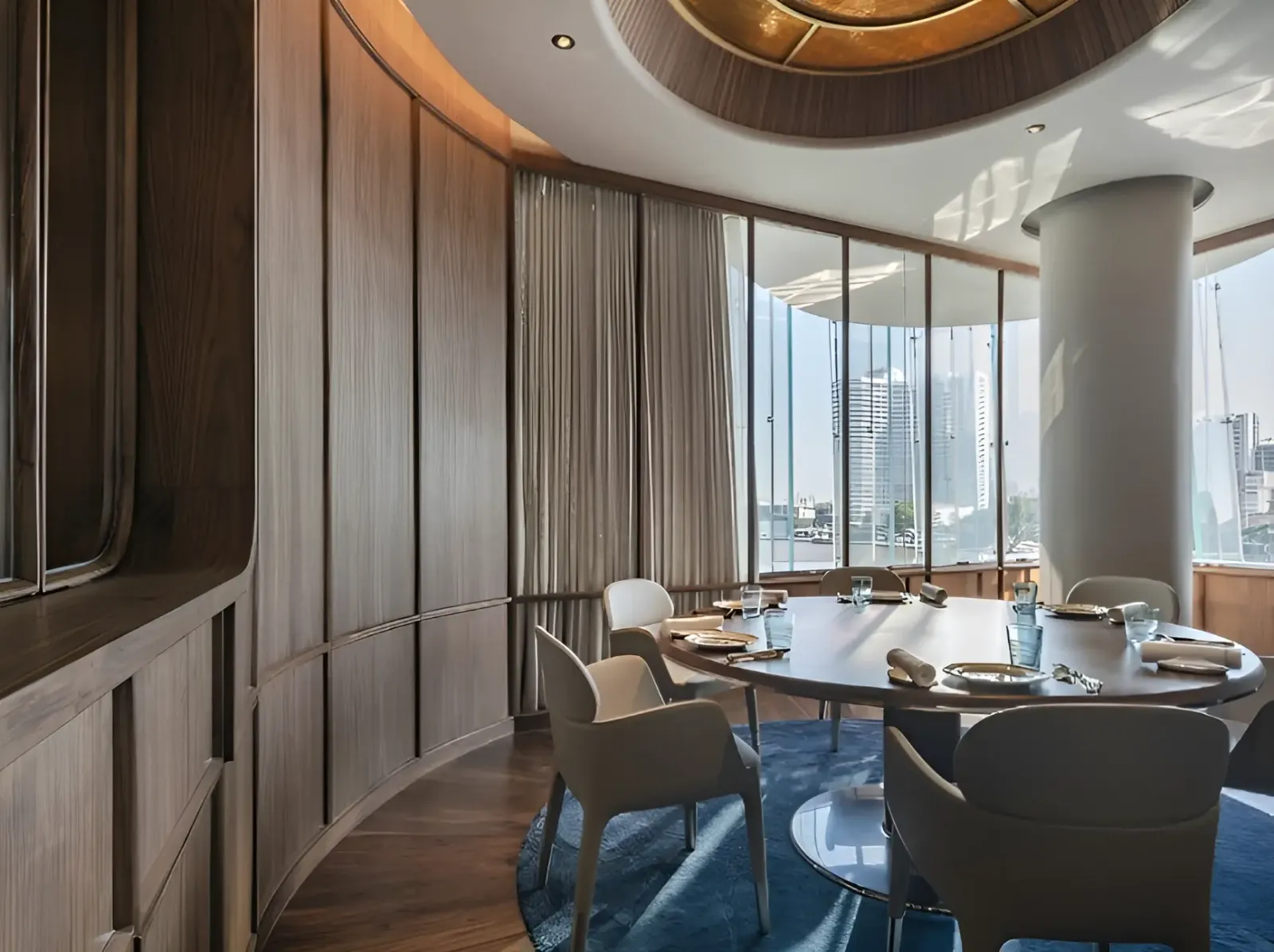 Blue by Alain Ducasse dining tables by the windows in daylight, with towers across the river