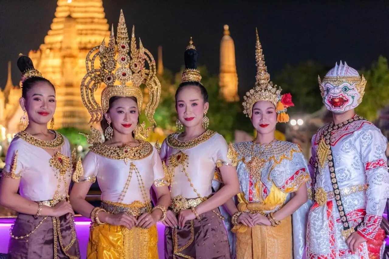 The dance troupe on deck with Wat Arun lit up in gold behind them