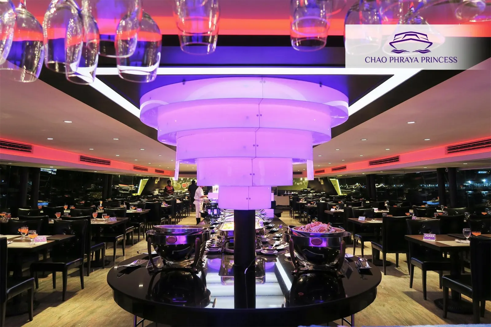 The Chao Phraya Princess dining deck with a glowing chandelier and set tables