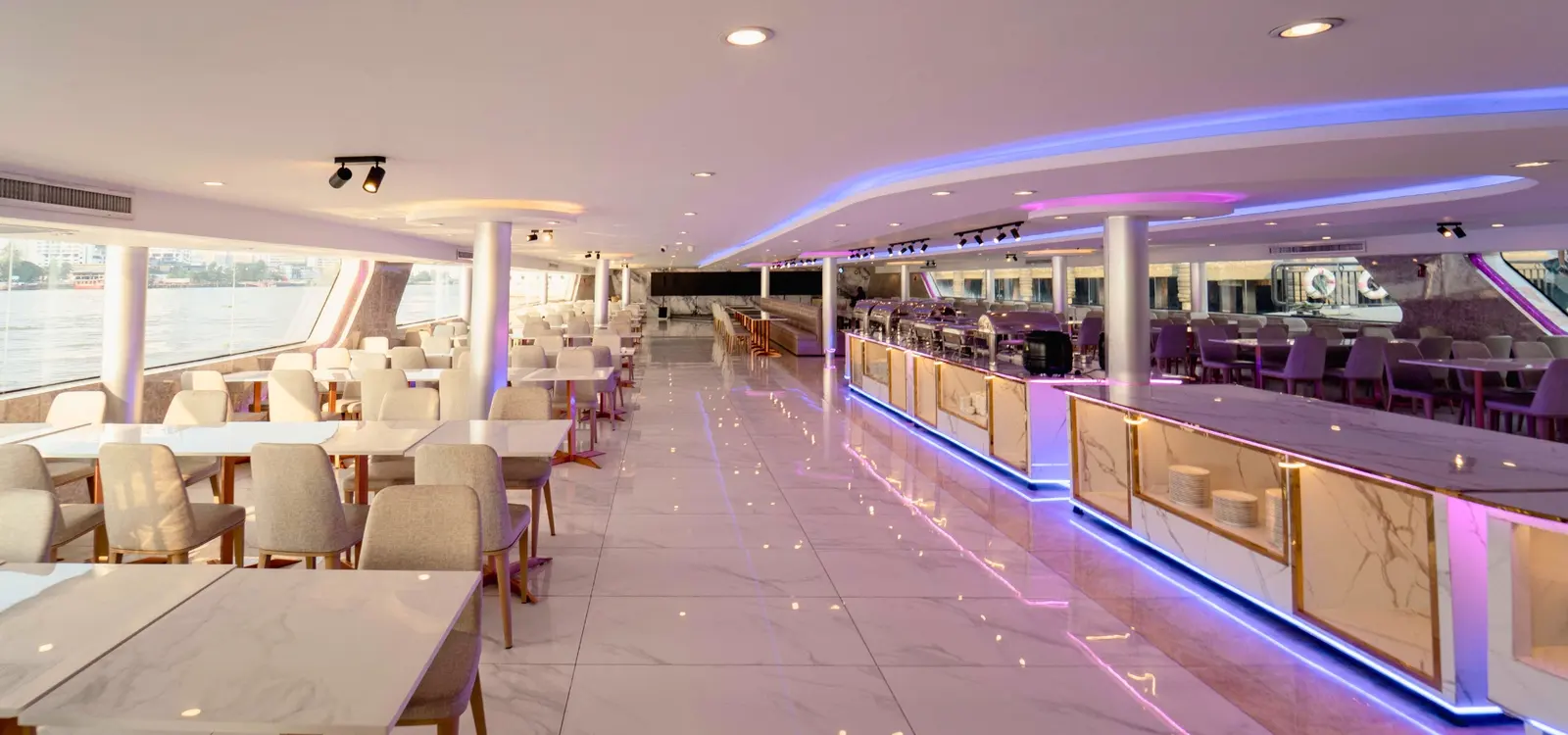 An air-conditioned dining deck on The Luxury White, with marble tables and a long buffet counter