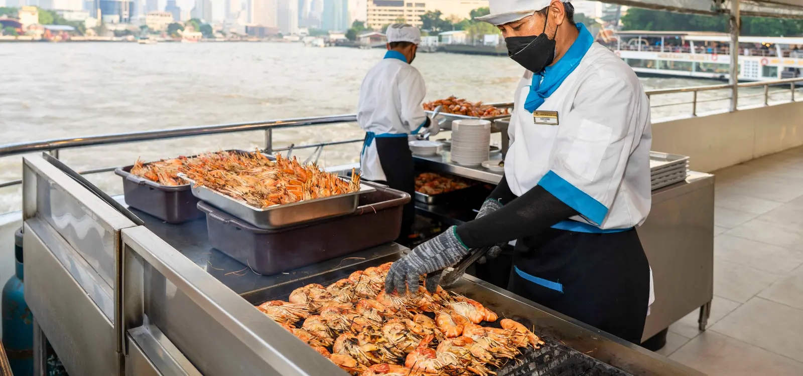 Chefs grilling river prawns on the open deck of The Luxury White