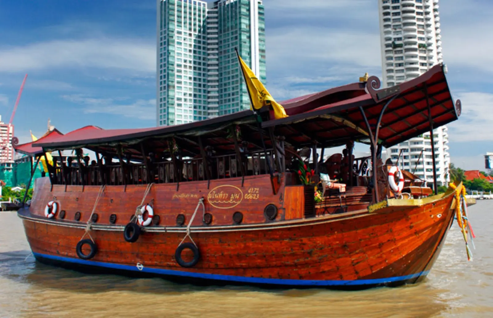 The Manohra dining barge with its wooden hull and red canopy on the Chao Phraya