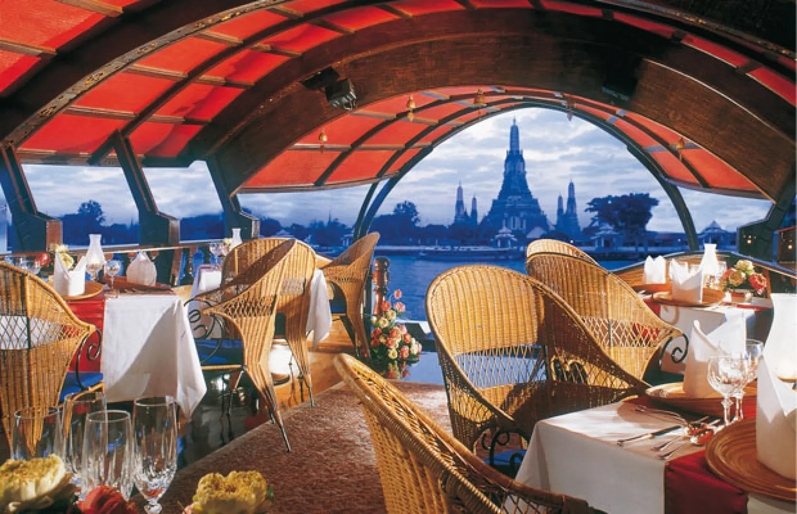 Tables under the red canopy of the Manohra, looking out to Wat Arun