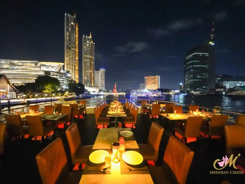Candlelit tables on the Meridian Cruise open deck at night, with ICONSIAM and riverside towers behind