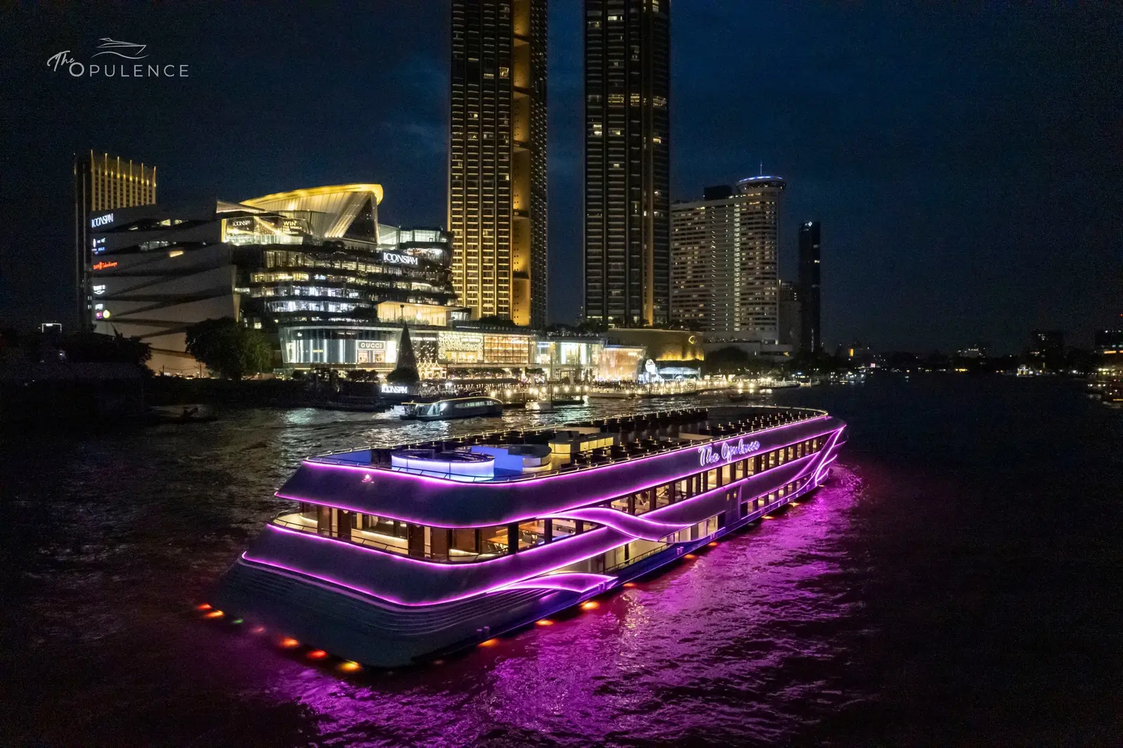 The Opulence lit up in purple on the river at night, with ICONSIAM behind
