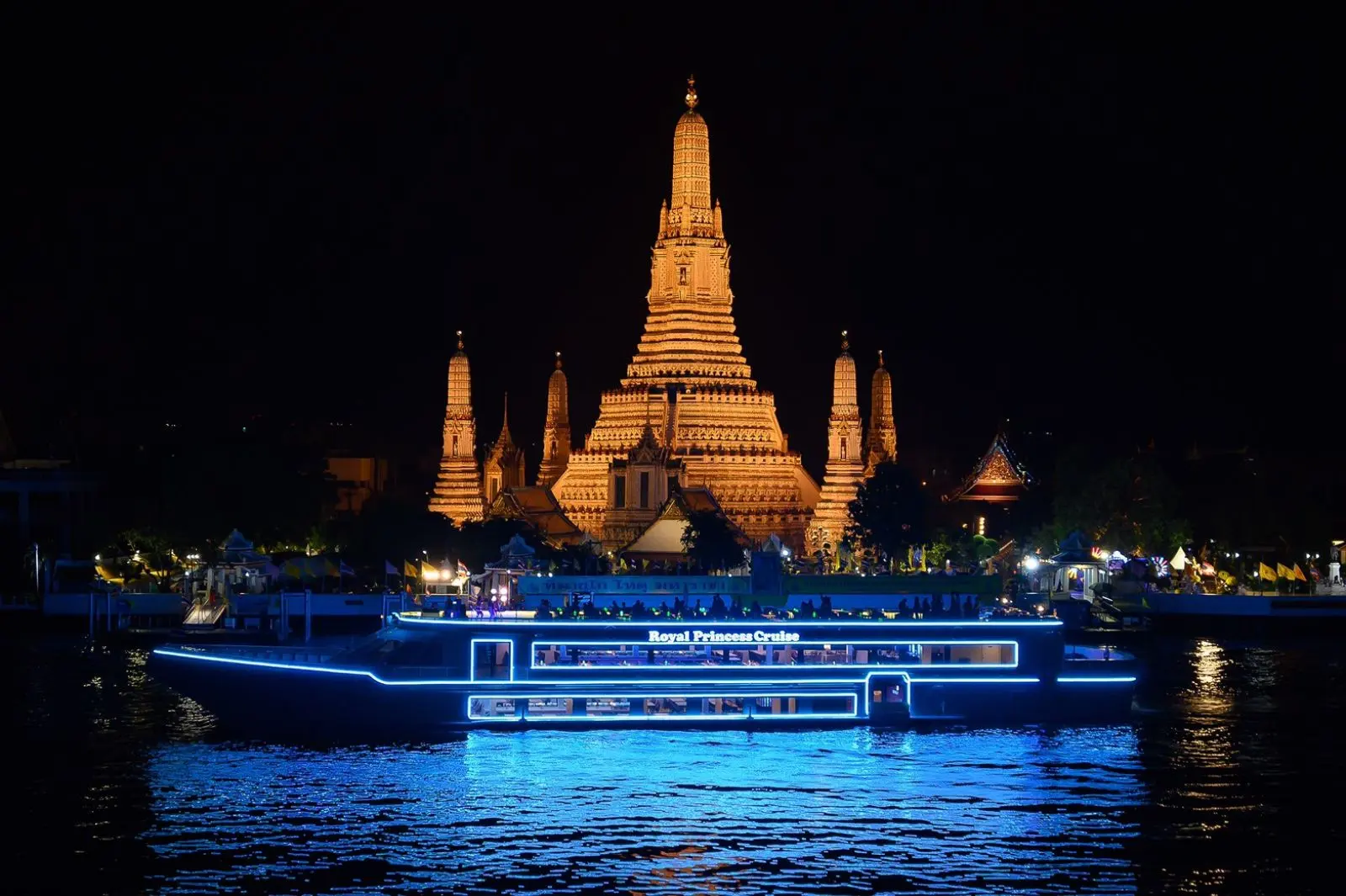 The Royal Princess Cruise lit in blue on the river at night, in front of Wat Arun