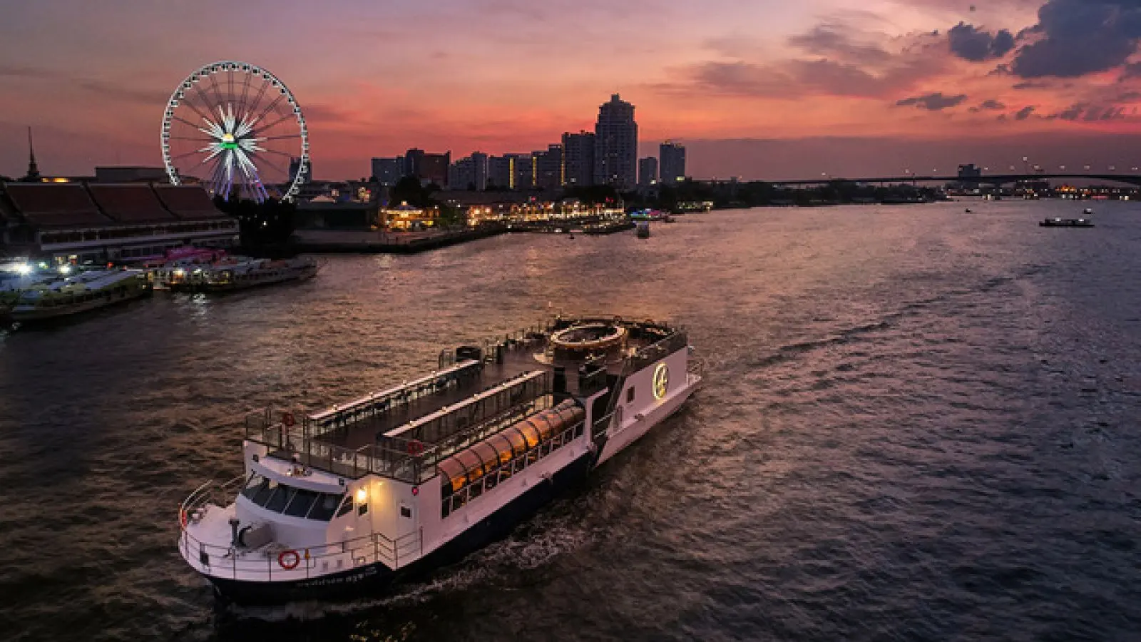 The Saffron Cruise boat on the river at sunset, with the Asiatique Ferris wheel behind