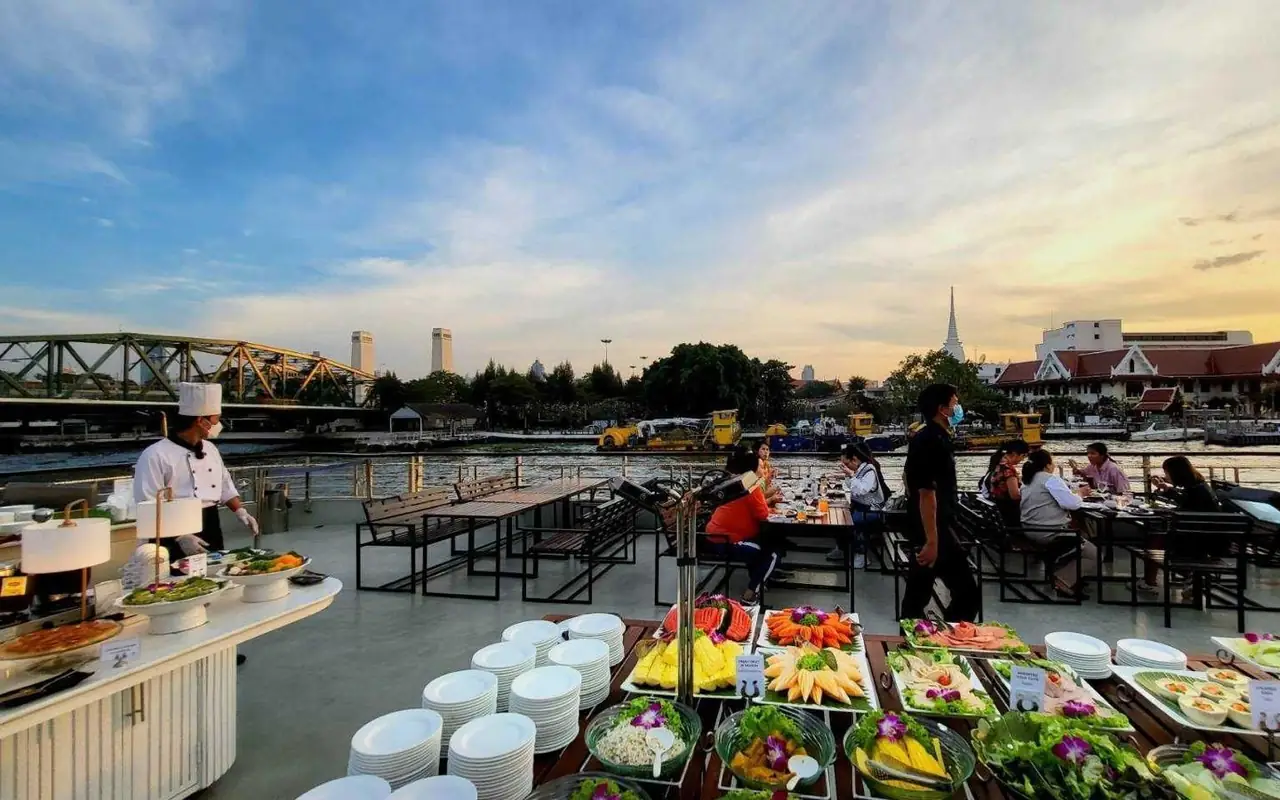 Guests dining at tables on the open top deck in the evening light