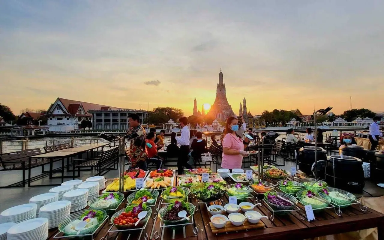 The buffet laid out on the open deck at sunset, Wat Arun on the far bank