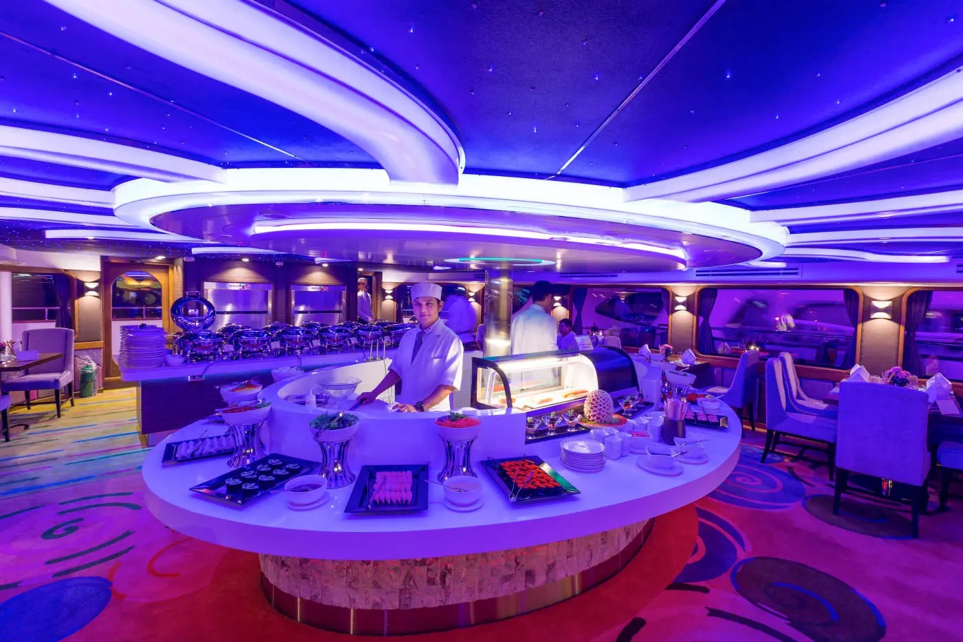 A chef at the round sushi station in the blue-lit dining room of Wonderful Pearl