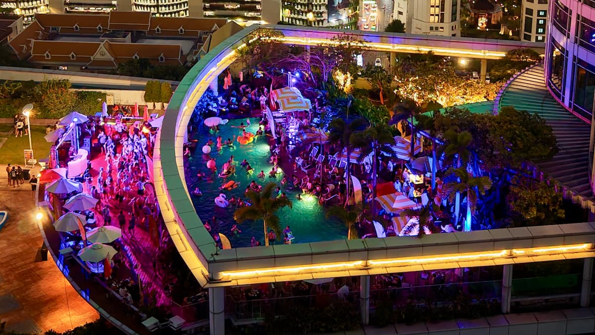 Aerial view of a Bangkok Rooftops pool party at dusk, the lit pool and the dance floor on the deck at Centara Grand at CentralWorld