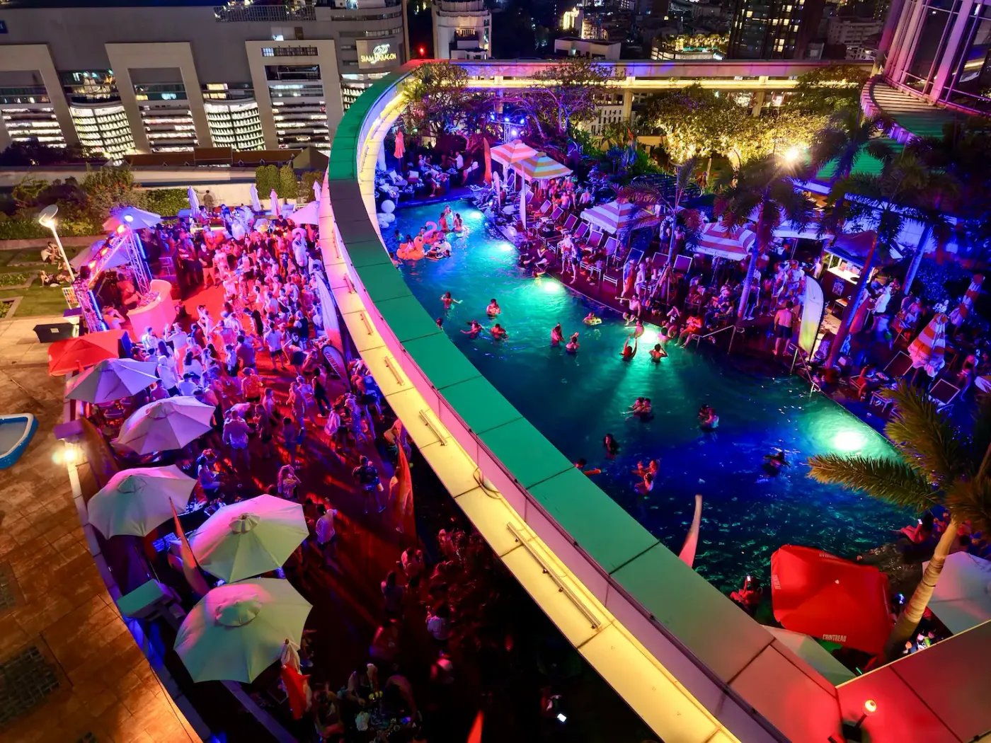 Drone view of a Bangkok Rooftops pool party in full swing on the Centara Grand pool deck at night