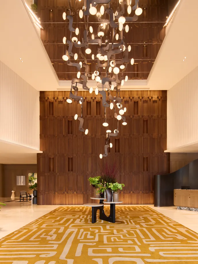 The lobby of Centara Grand at CentralWorld, a tall chandelier over a gold patterned carpet