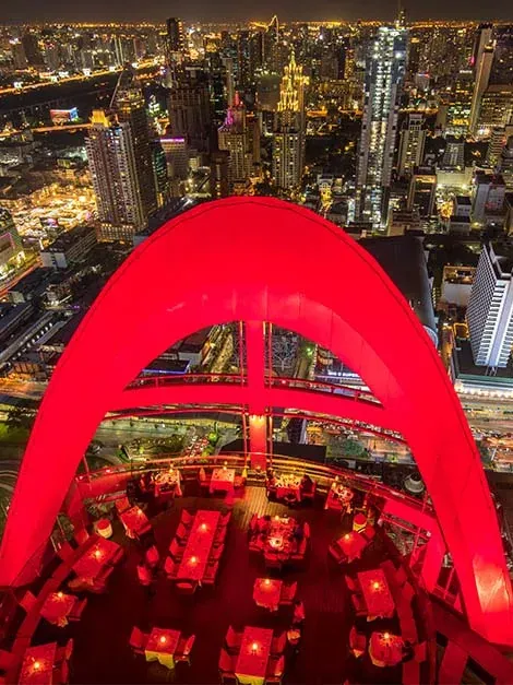 Red Sky's red arch on the roof of Centara Grand at CentralWorld, the city lit up below