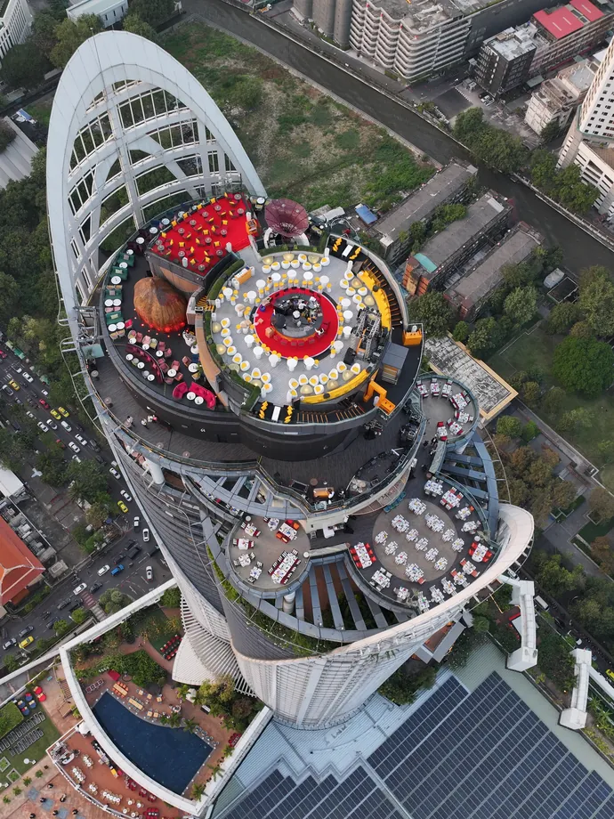 The top of Centara Grand at CentralWorld seen from above by day, its rooftop bars under a white arch