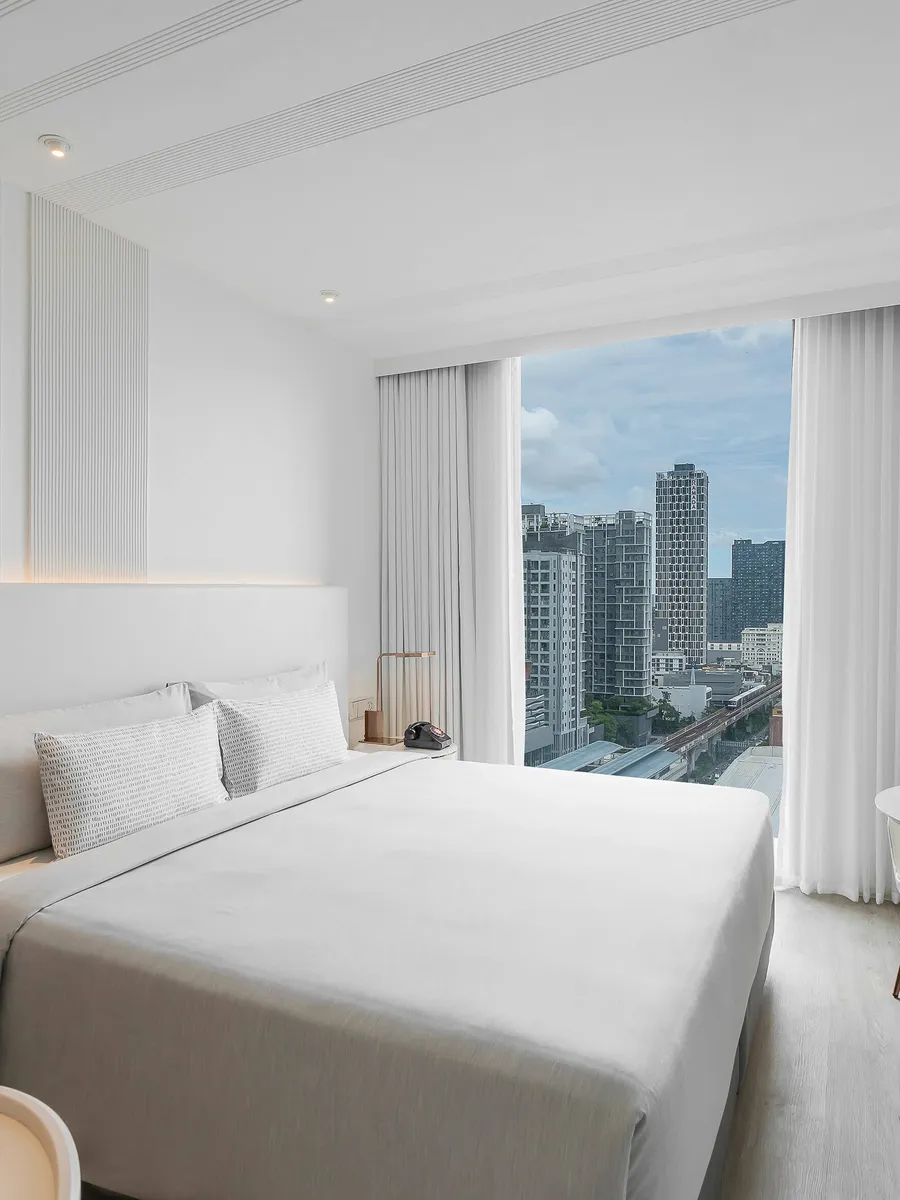 An INNSiDE Room King at INNSiDE by Meliá Bangkok Sukhumvit, a white bed by a window onto the city