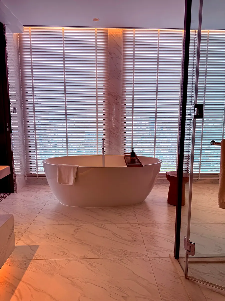 A freestanding bathtub by the window in a Kimpton Maa-Lai Bangkok bathroom