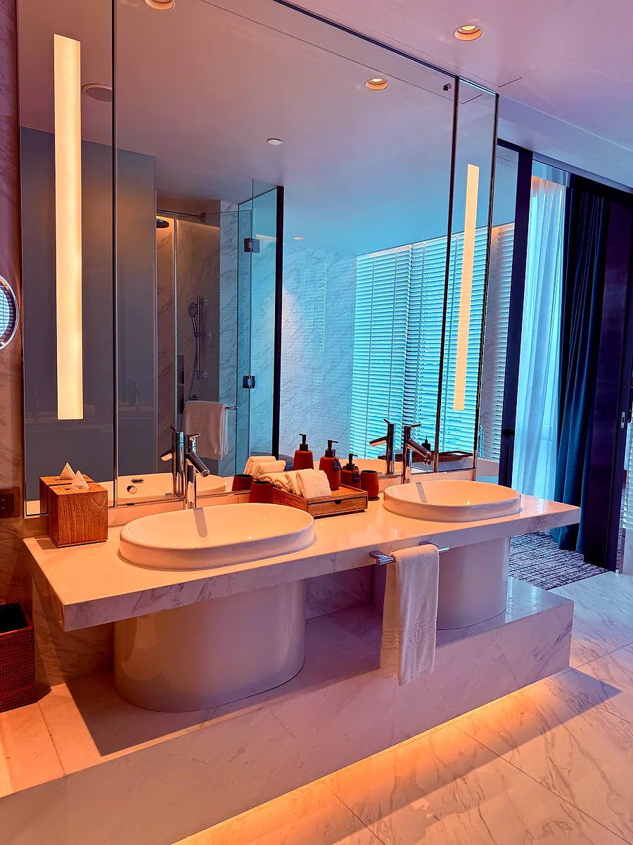 A marble double vanity with backlit mirrors in a Kimpton Maa-Lai Bangkok bathroom