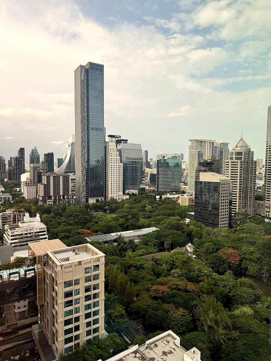 The view from a high floor of Kimpton Maa-Lai Bangkok, a green park below and city towers behind