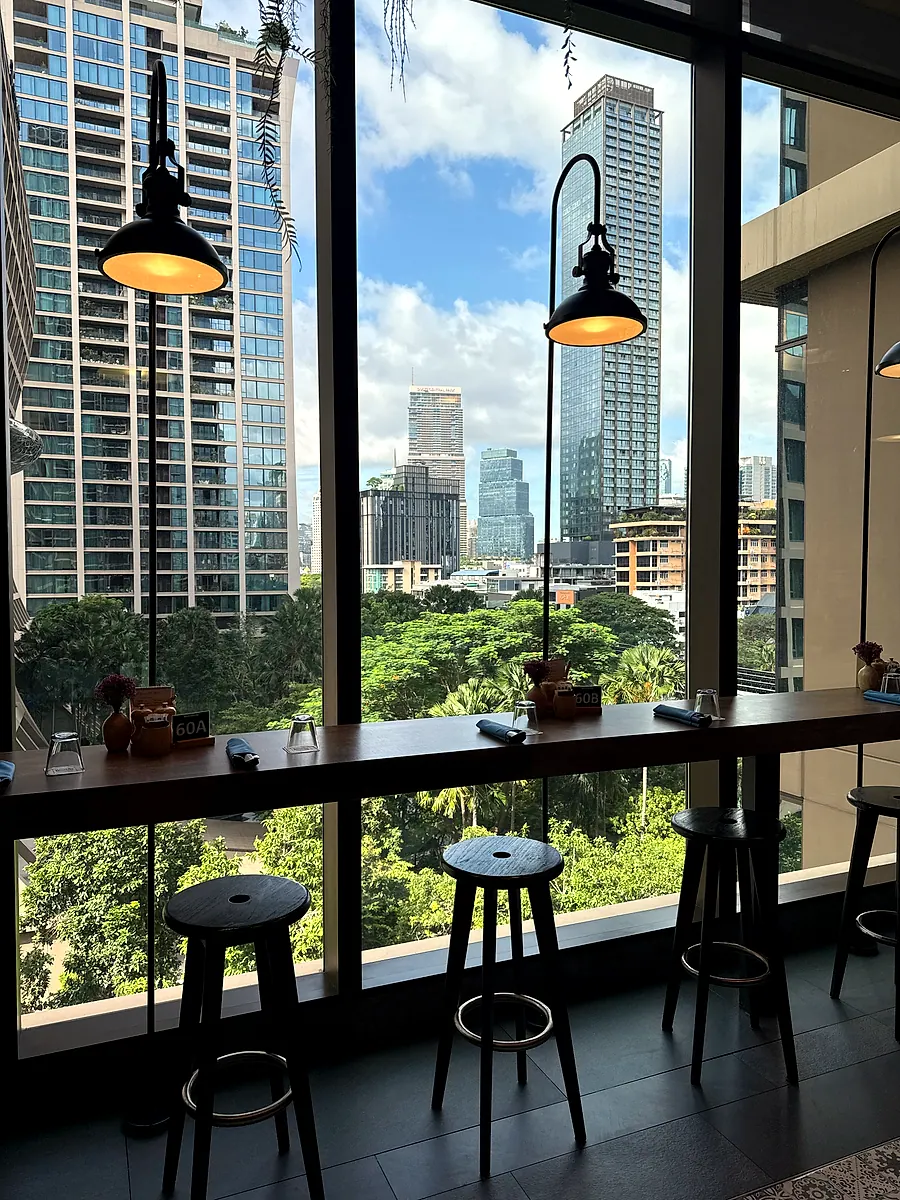 Window seats at Kimpton Maa-Lai Bangkok looking onto the trees and towers outside