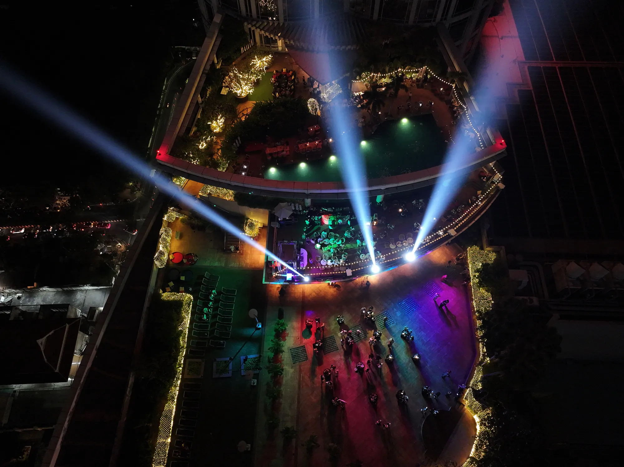 The 26th-floor pool deck and garden of Centara Grand after midnight on New Year's Eve 2025, light beams over the stage