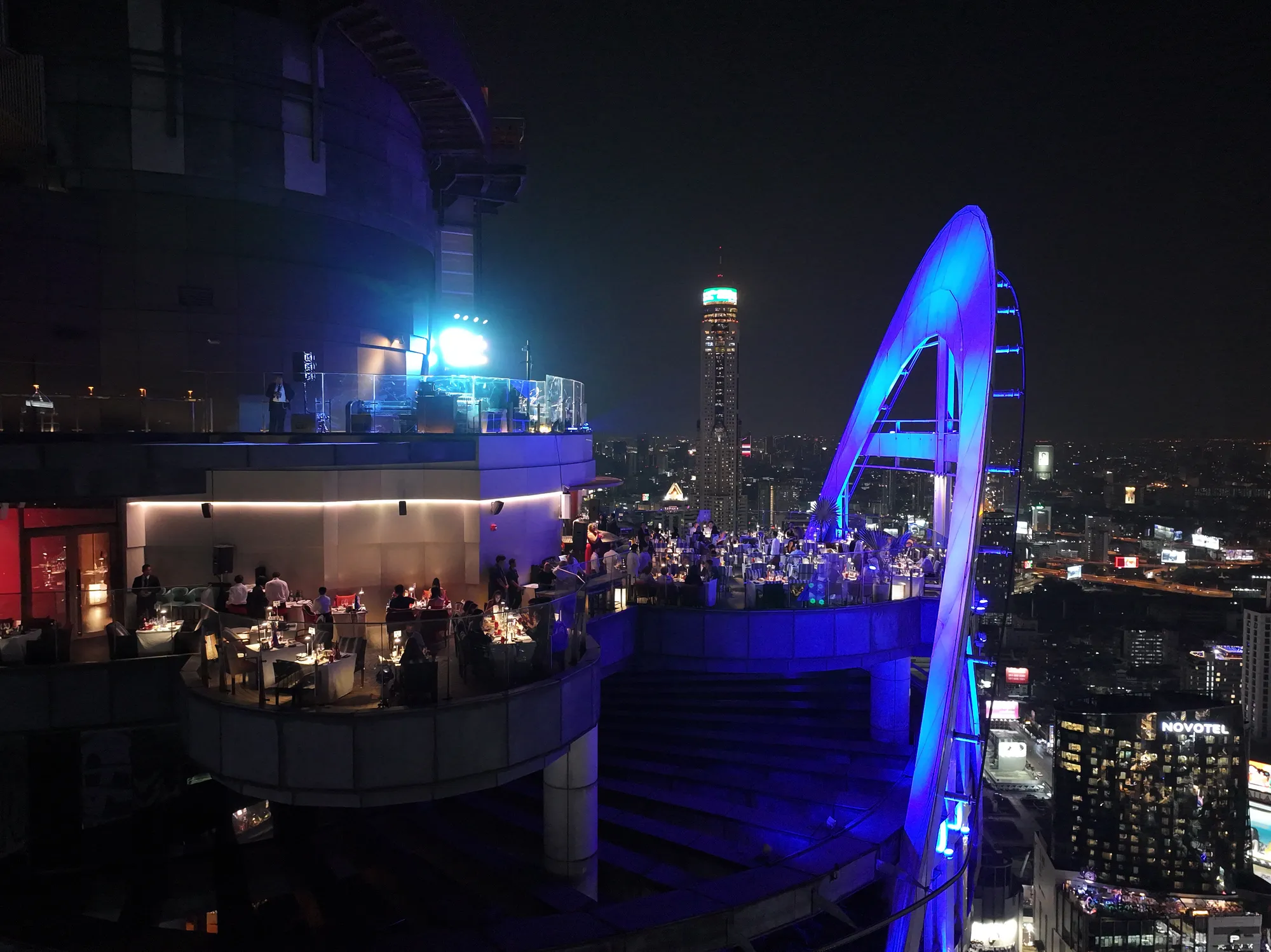 Red Sky Bar's terrace on New Year's Eve 2025 with the arch lit blue and the city behind
