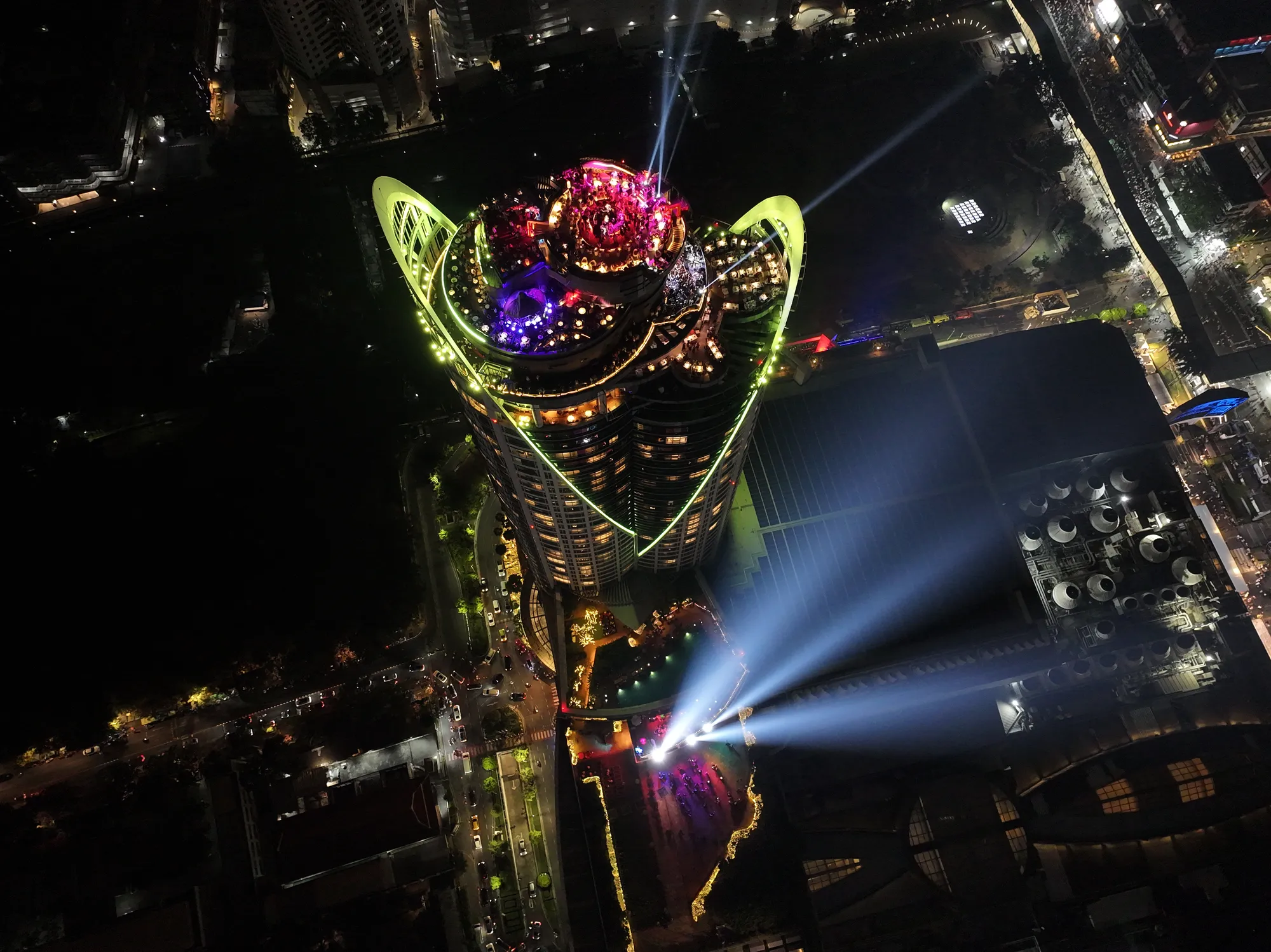 The top of the Centara Grand tower lit green and yellow after midnight on New Year's Eve 2025