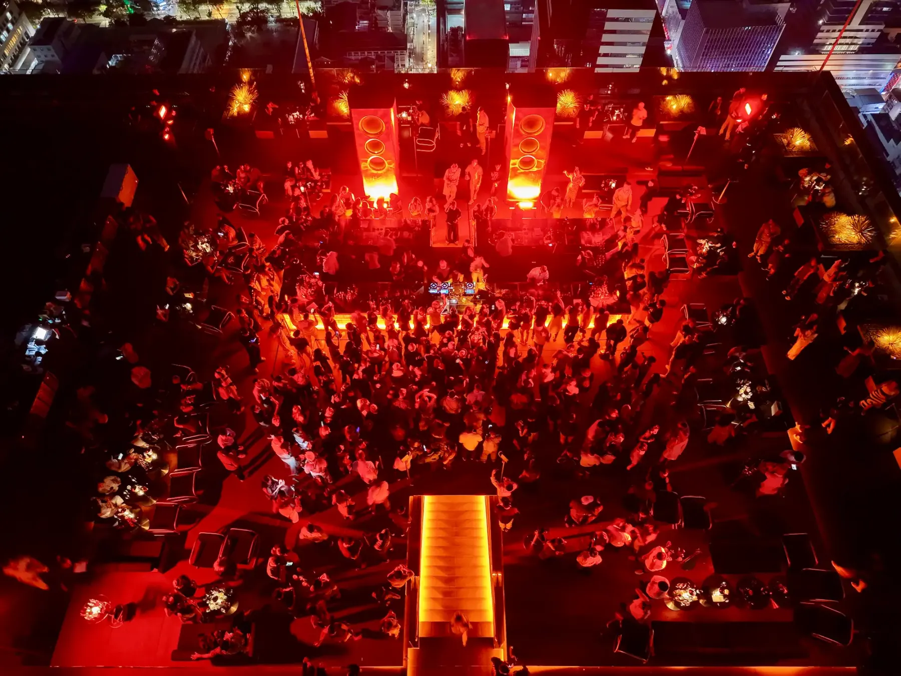 Top-down drone view of a dense crowd filling the red-lit dancefloor at Aether in front of the DJ booth