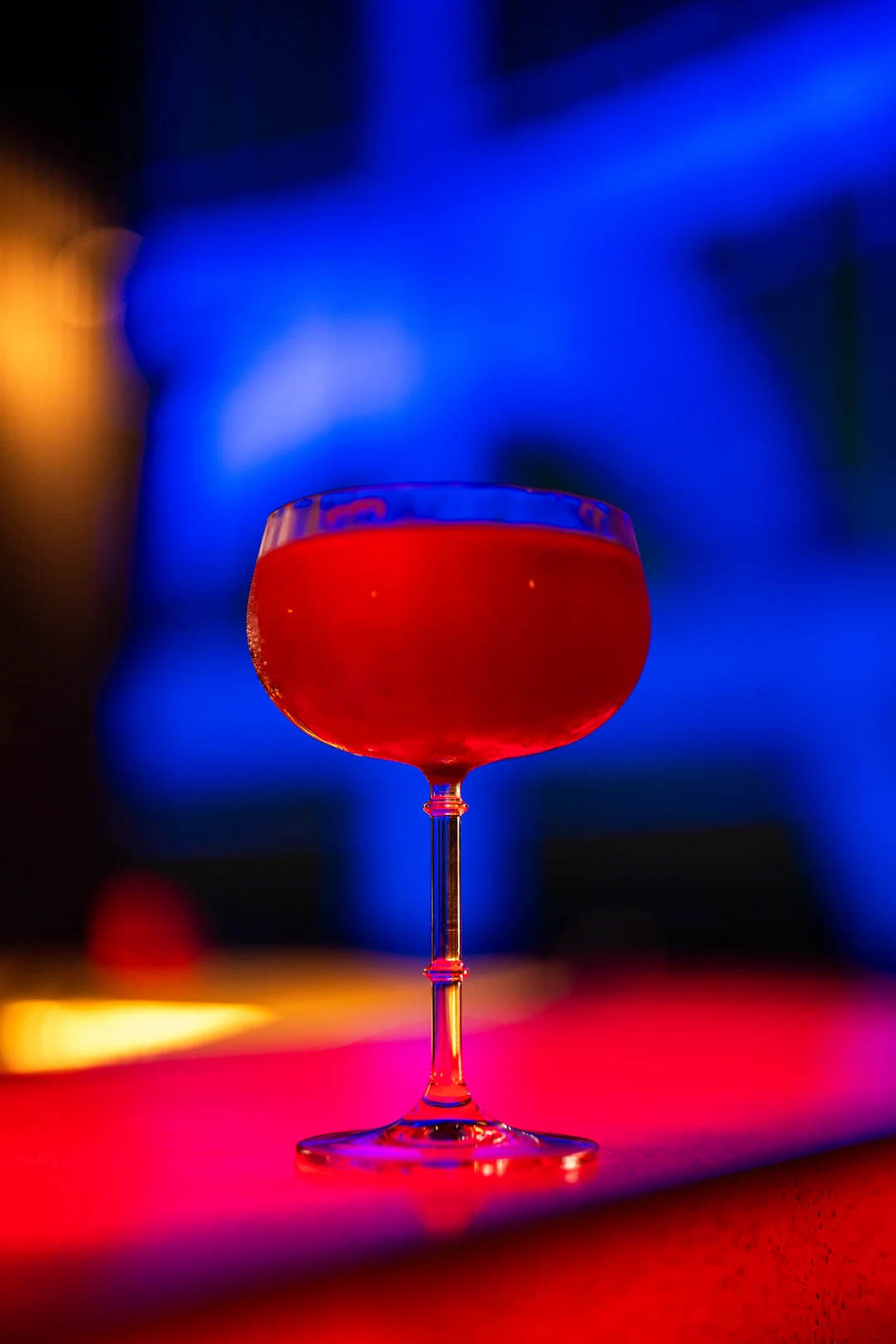 A cocktail glowing under blue and red neon light on the Cocoa XO bar