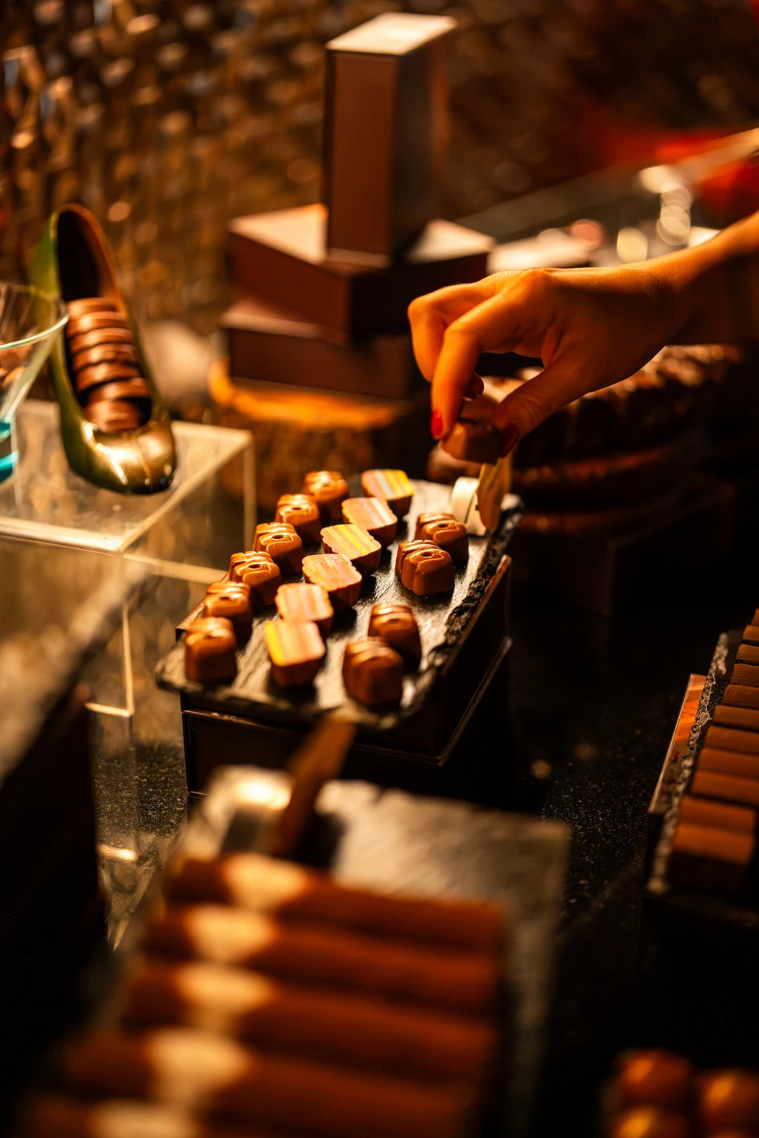 A guest choosing from a slate of handcrafted pralines and truffles at Cocoa XO
