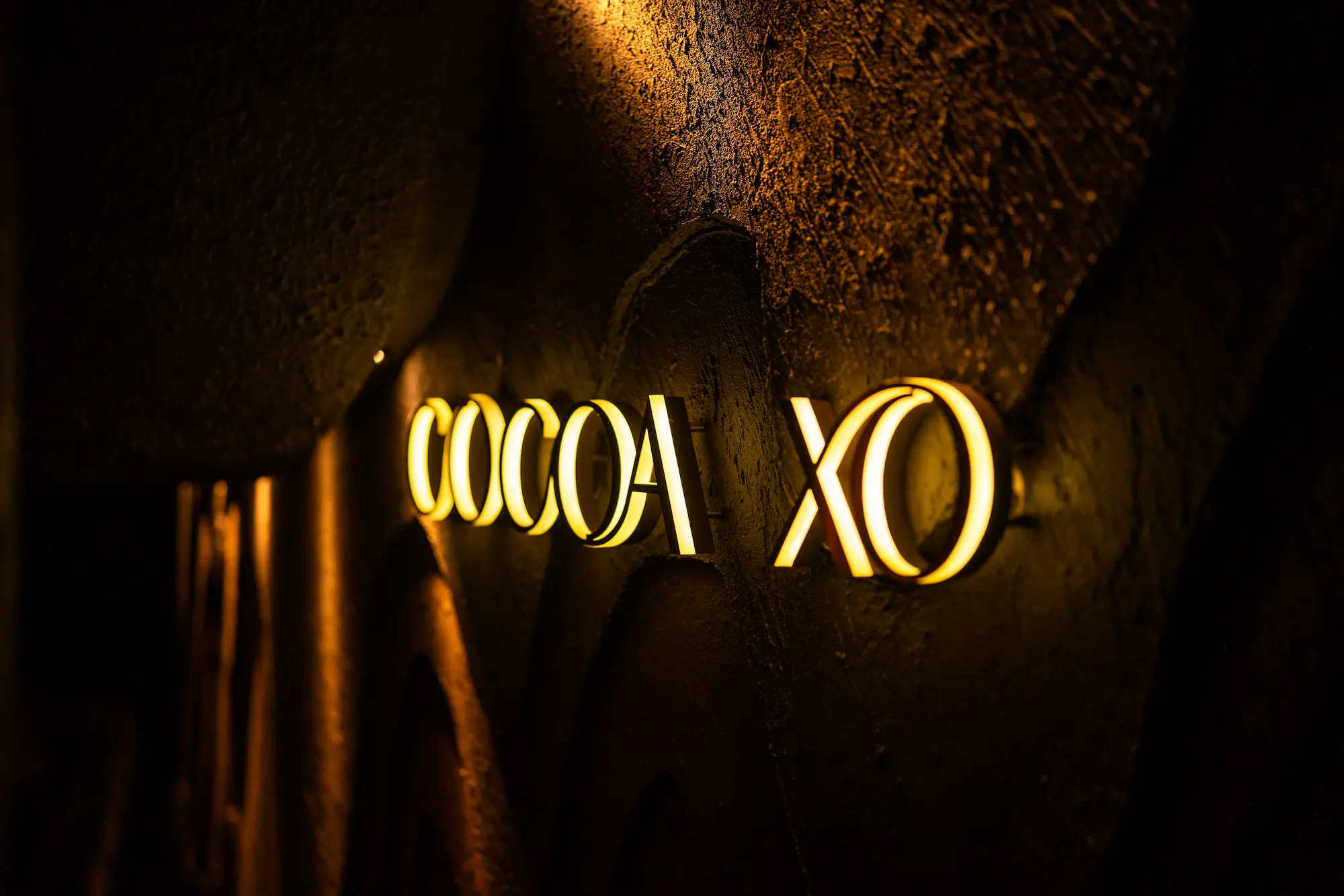 The illuminated COCOA XO signage glowing on the cave wall