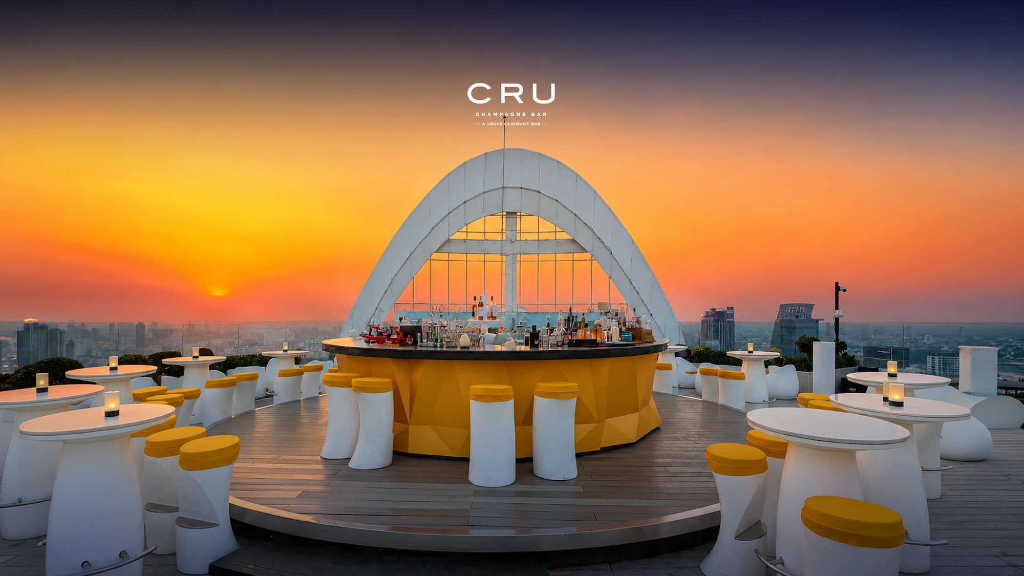 CRU Champagne Bar's circular bar under its white arched canopy on the open-air rooftop deck at sunset, the Bangkok skyline wrapping around 59 floors below