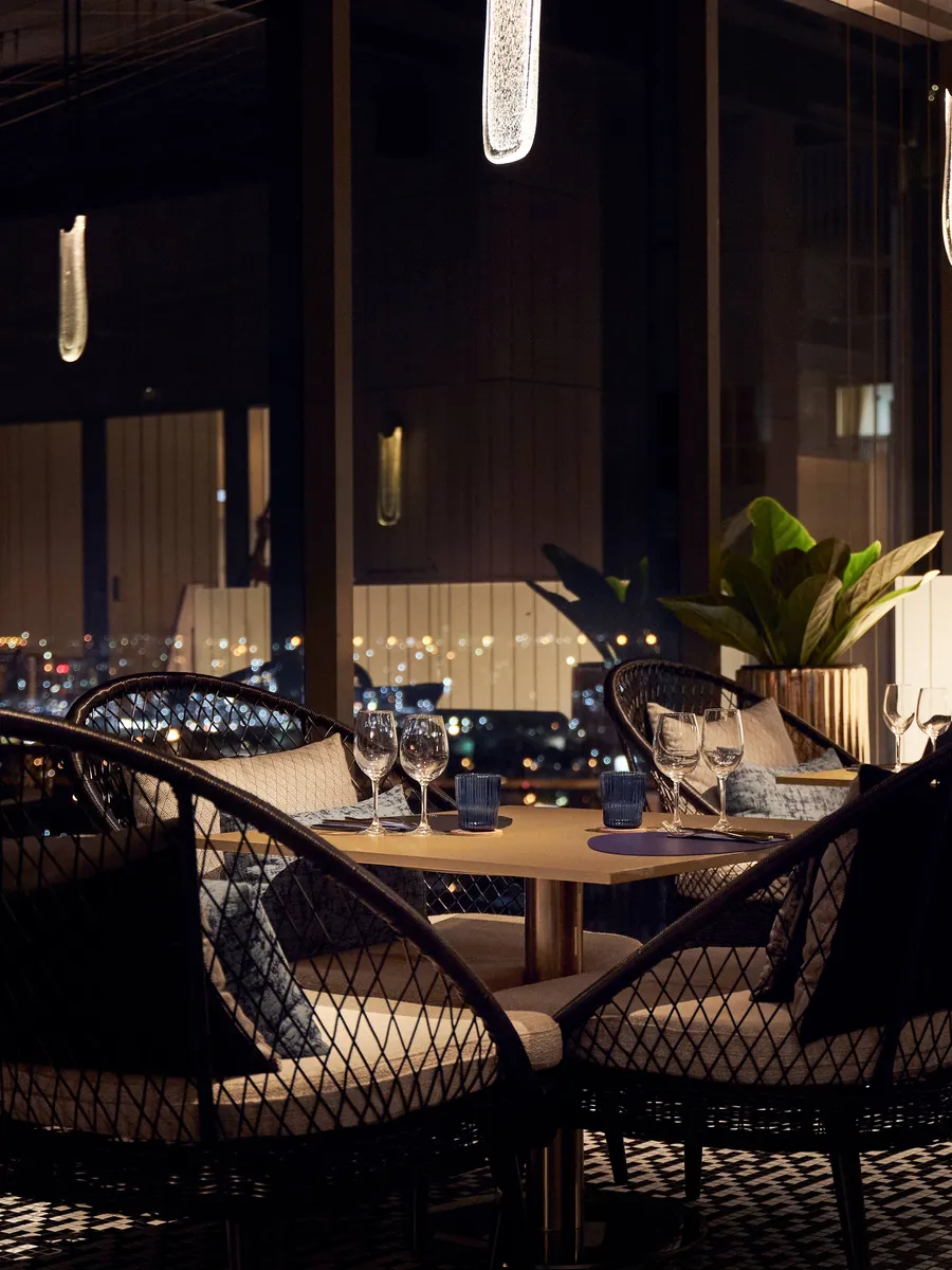 A table set for dinner by the window at LUZ Bangkok Tapas Bar at night