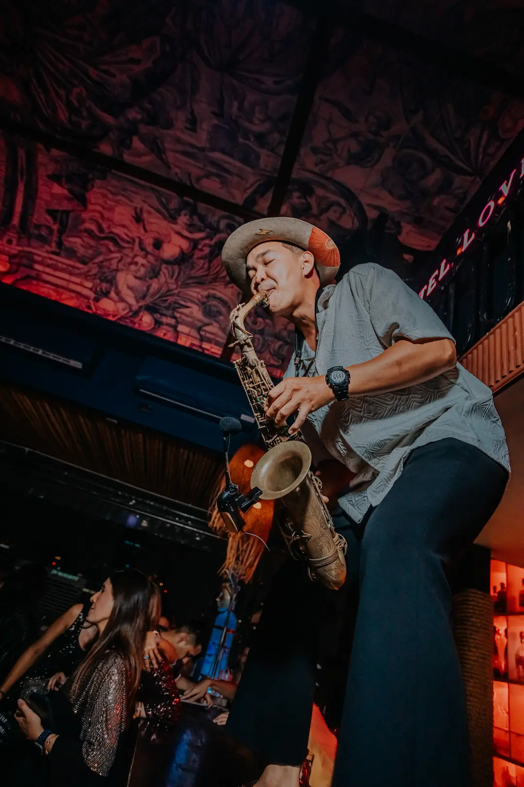 A saxophonist playing live on the bar at Pastel while the crowd dances below