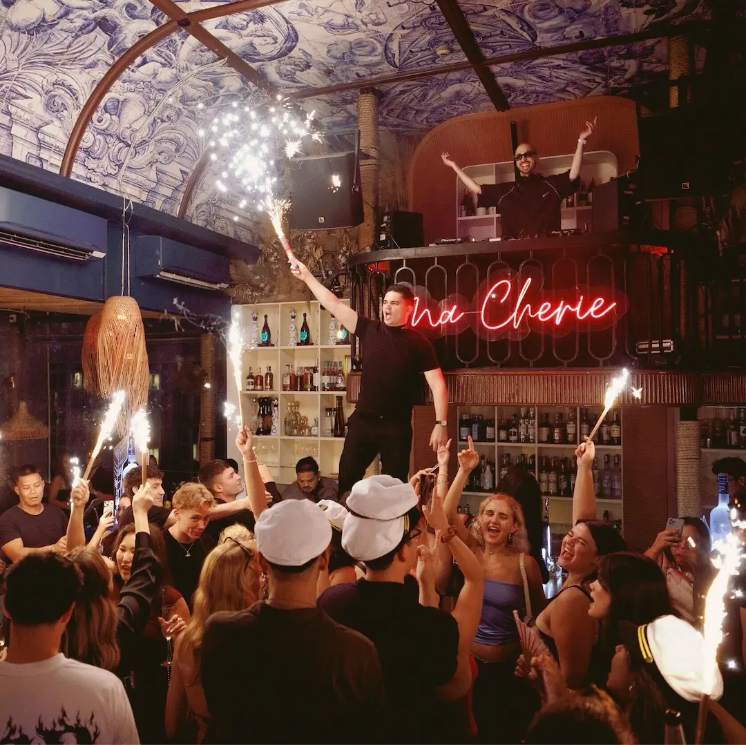 The Pastel crowd cheering with sparklers as the DJ plays overhead, under the hand-painted blue-and-white dome