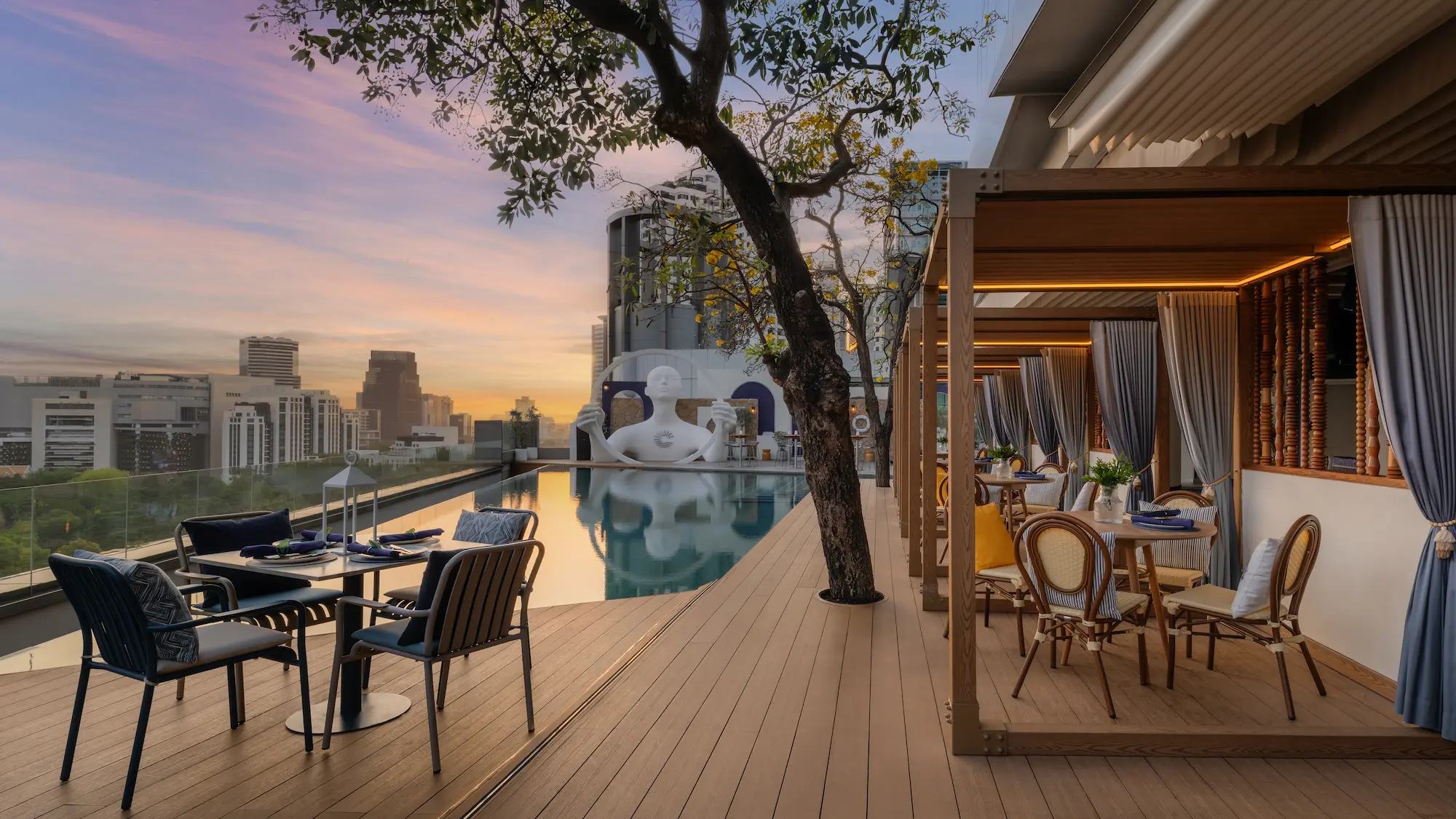 Poolside cabana seating and reflecting pool at sunset on the View rooftop, Bangkok