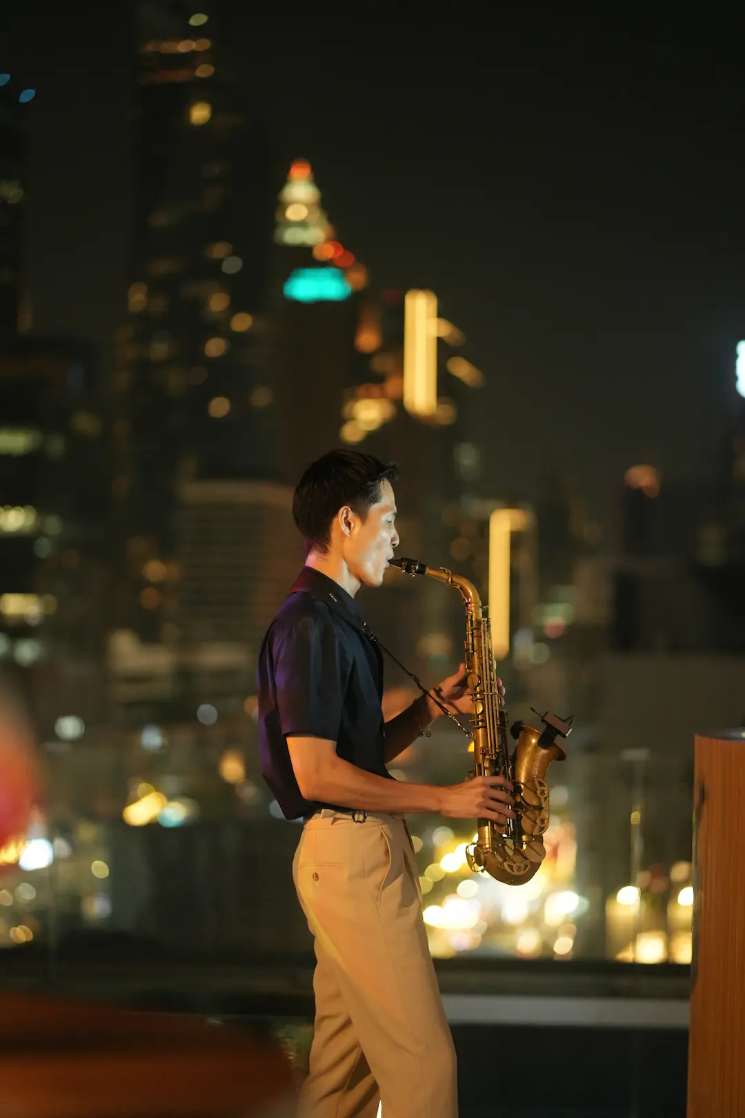 Live saxophonist performing against the Bangkok night skyline at View rooftop