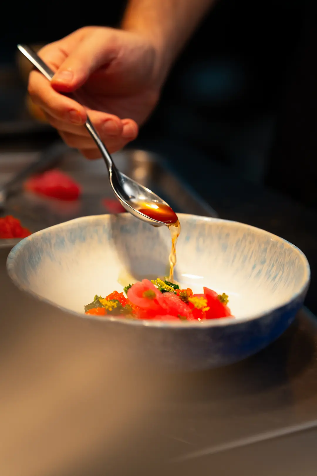 Close-up of tuna crudo being finished with a drizzle of dressing at View rooftop, Bangkok